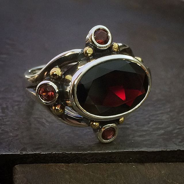 A little on the dark side. Blood red garnets! The centre stone appears black then you get a flash of deep red. Sterling Silver with 22ct Gold Granules. There is a medieval feel to to this ring. Size P